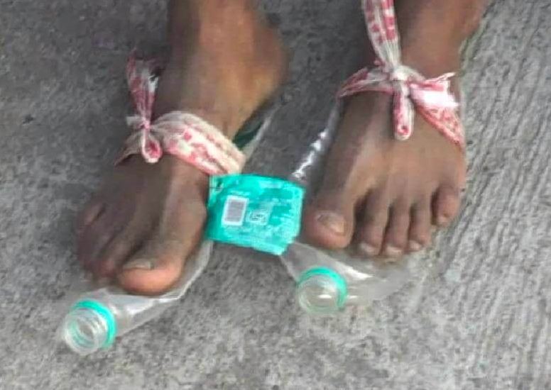 चप्पल घिस जाने के बाद पैरों में बिसलेरी की बोतल डाल कर चलता एक मज़दूर।