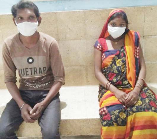 पैदल चलने के बाद रास्ते में आराम करते मज़दूर पति-पत्नी।