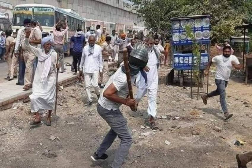 सादे ड्रेस में किसानों पर लाठी बरसाता एक शख्स।